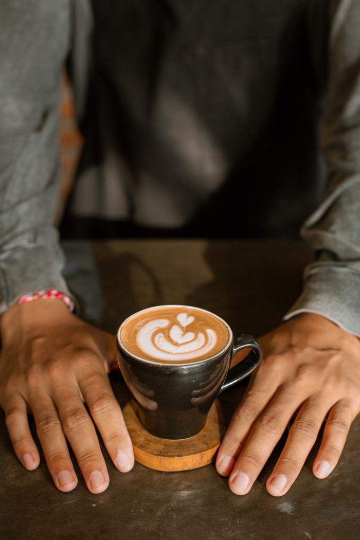 Crafting Captivating Headlines: Your awesome post title goes here Warm coffee with intricate latte art held on a table, framed by relaxed hands.